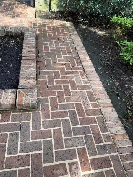 The same herringbone brick walkway after cleaning, brick color and pattern visible