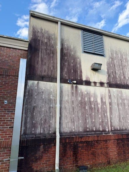 Commercial building wall with heavy dark weathering streaks down the panels