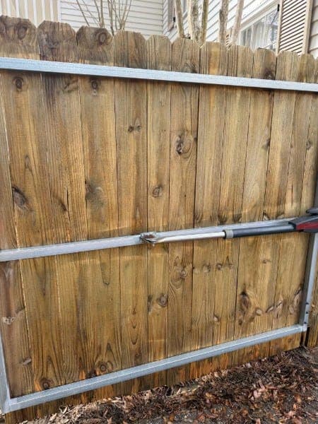 The same wooden fence after cleaning, showing clean golden wood grain