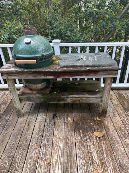 Weathered gray deck boards and a wooden grill table before cleaning