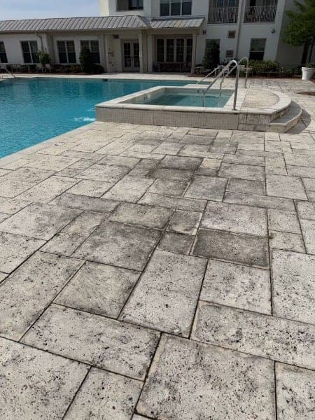 Pool deck pavers mottled with dirt and staining before cleaning
